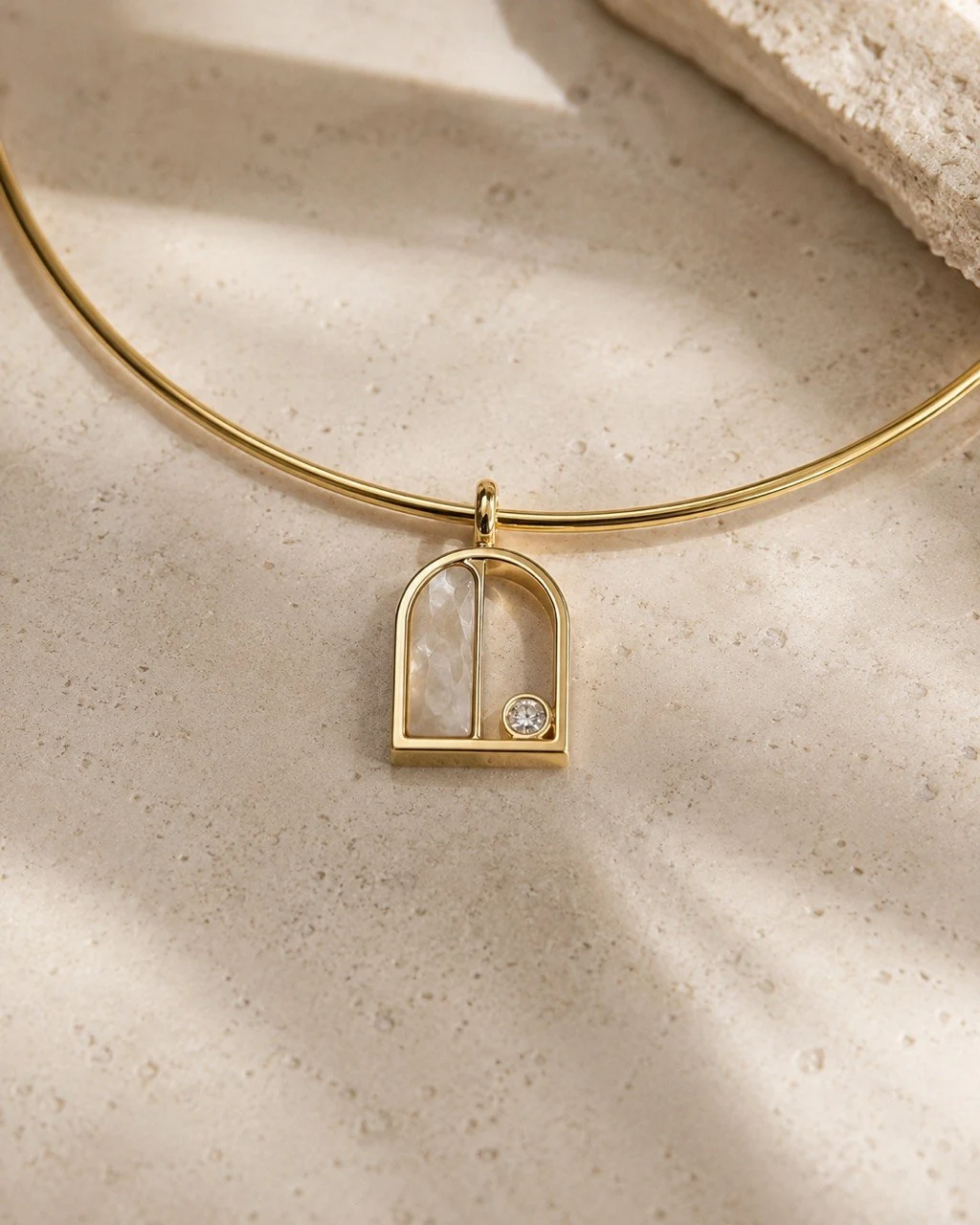 A gold architectural pendant on pale stone